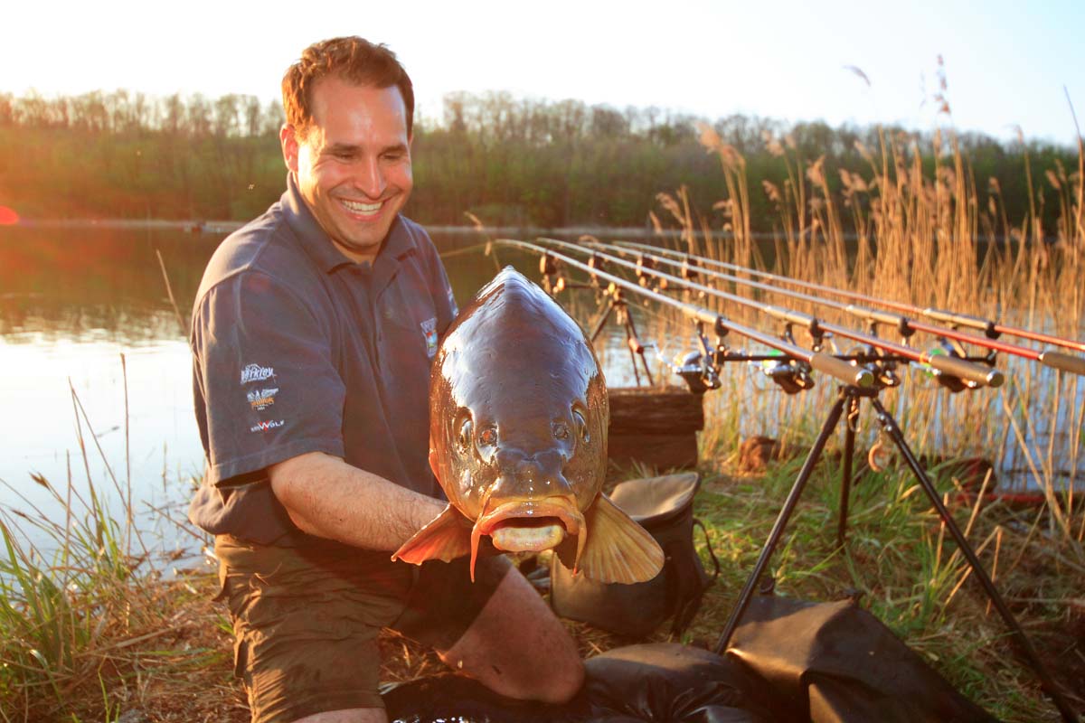 Karpfenangler mit Fisch hat die Fehler beim Karpfenangeln vermieden