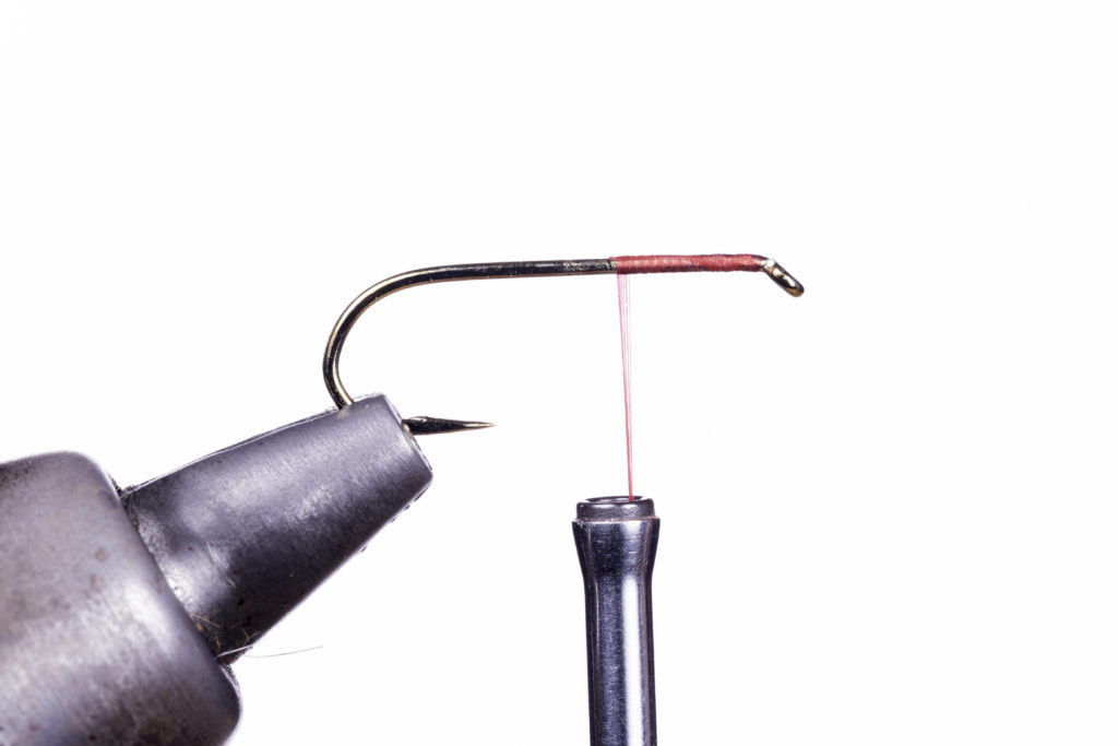 Fliegenbinden 4. Jetzt können Sie den Bobbin loslassen und durchatmen – Ihre erste Grundwicklung ist fast fertig, Sie haben den Faden (ohne Knoten oder Klebstoff) perfekt fixiert.
