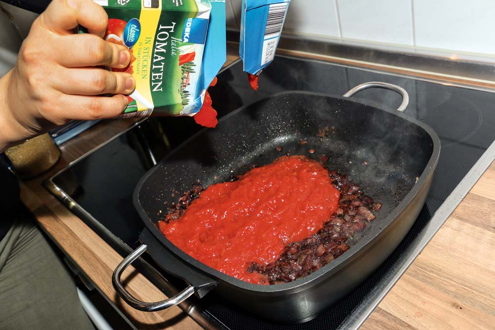 Tomatenstückchen und eine gute Prise Zucker hinzugeben. Nun eine gute halbe Stunde kochen lassen, bis die Sauce dickflüssiger ist.