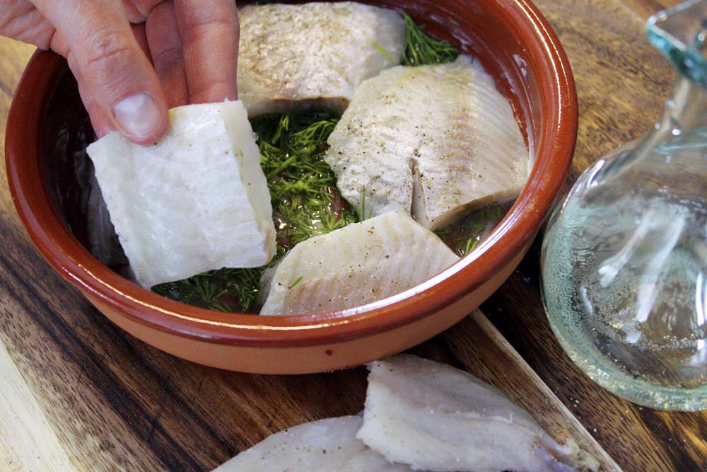 Die Auflaufform mit Butter einpinseln. Anschließend den Wein sowie den zerkleinerten Dill zugeben und die Fischfilets nun darin platzieren.