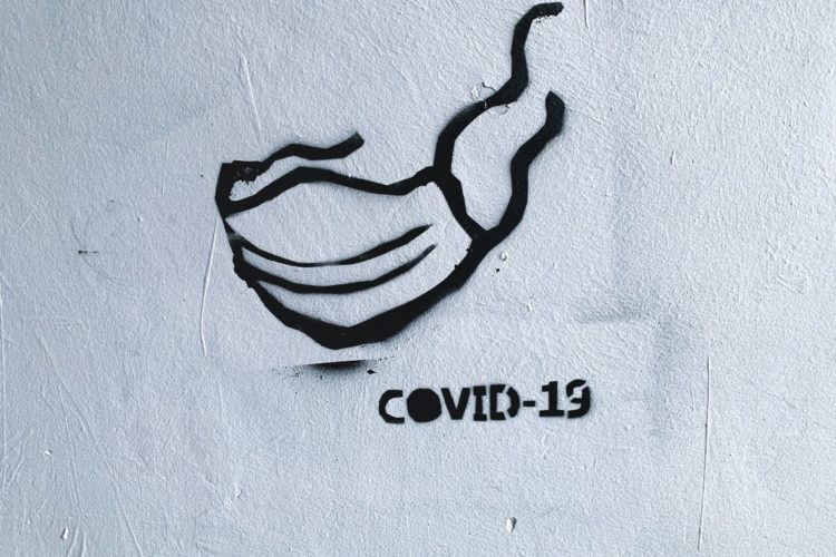 Ausgangssperre: Ein Graffiti an einer Häuserwand zeigt eine Maske und einen Schriftzug mit "Covid-19"
