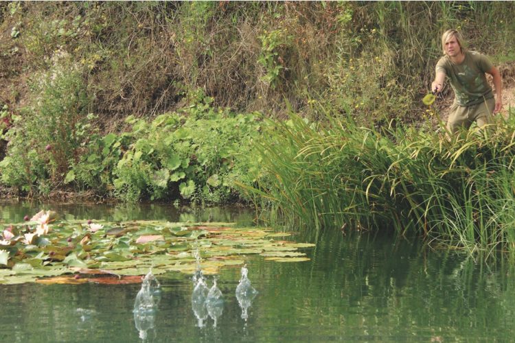 Angler an der Uferkante eines Baggersees wirft die Angel aus.