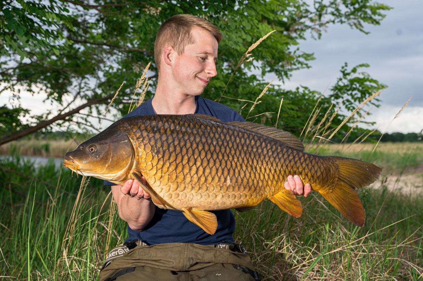 Angler mit goldenem Schuppenkarpfen