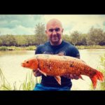 Craig Kent an einem Teich der Woodland Lakes Fisheries mit einem Ghostkarpfen.