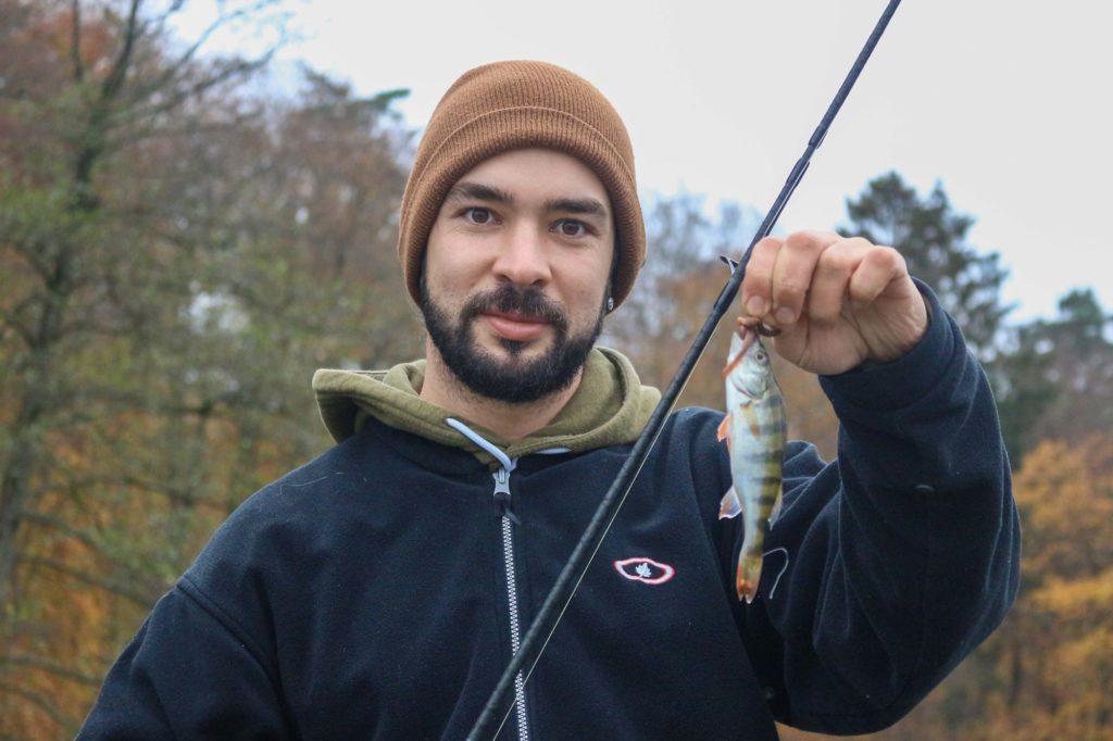 Angler im Herbst mit kleinem Barsch