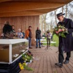 Mann legt Blumenstrauß an Sarg voller Wasser nieder