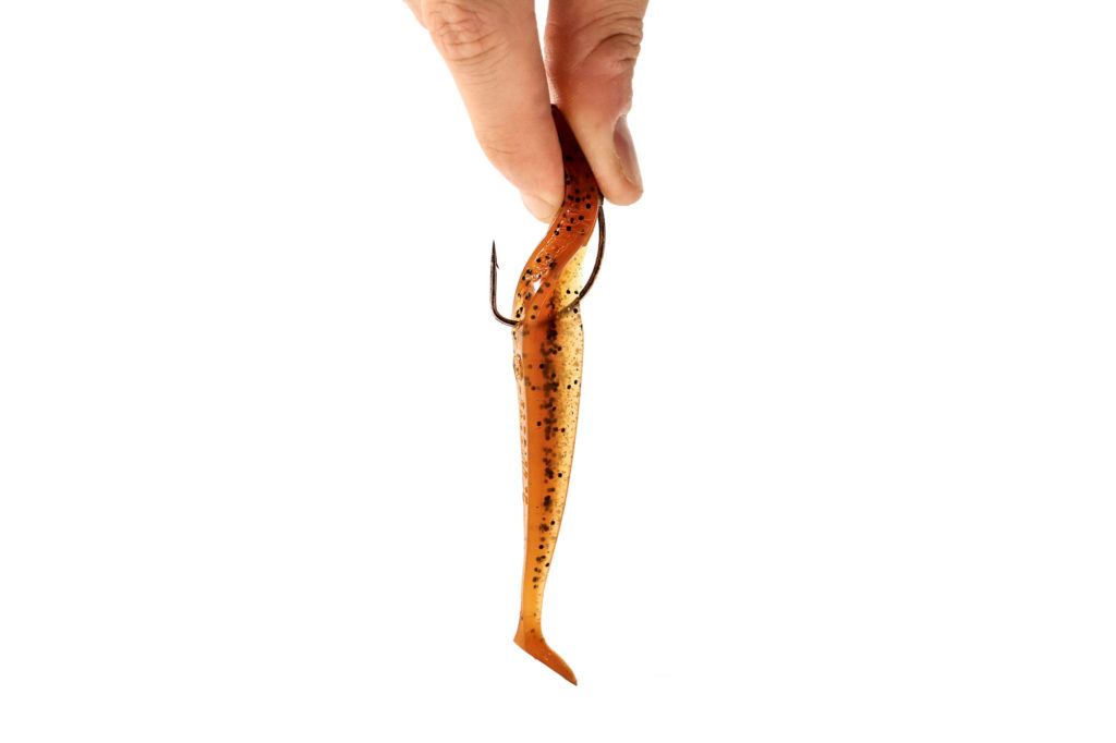 Zwei Finger quetschen einen Gummifisch am Offsethaken beispielhaft zusammen, wie ein Raubfisch den Köder fressen würde