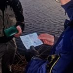 Ein Angler wird von der Fischereiaufsicht kontrolliert.