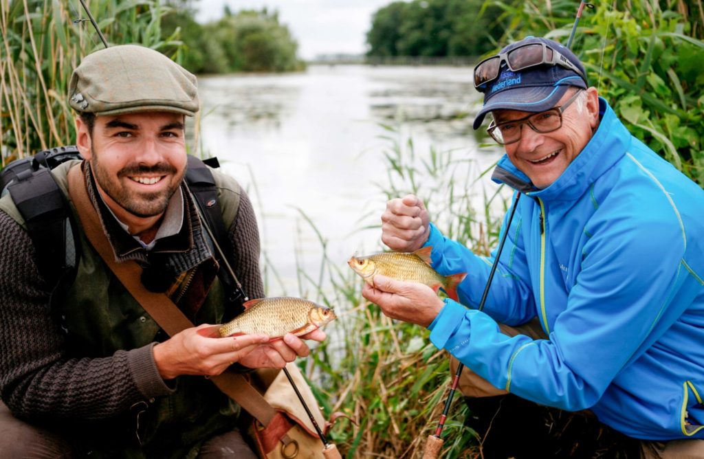 Zwei holländische Angler präsentieren kleine Rotfedern, die sie in einem Polder gefangen haben