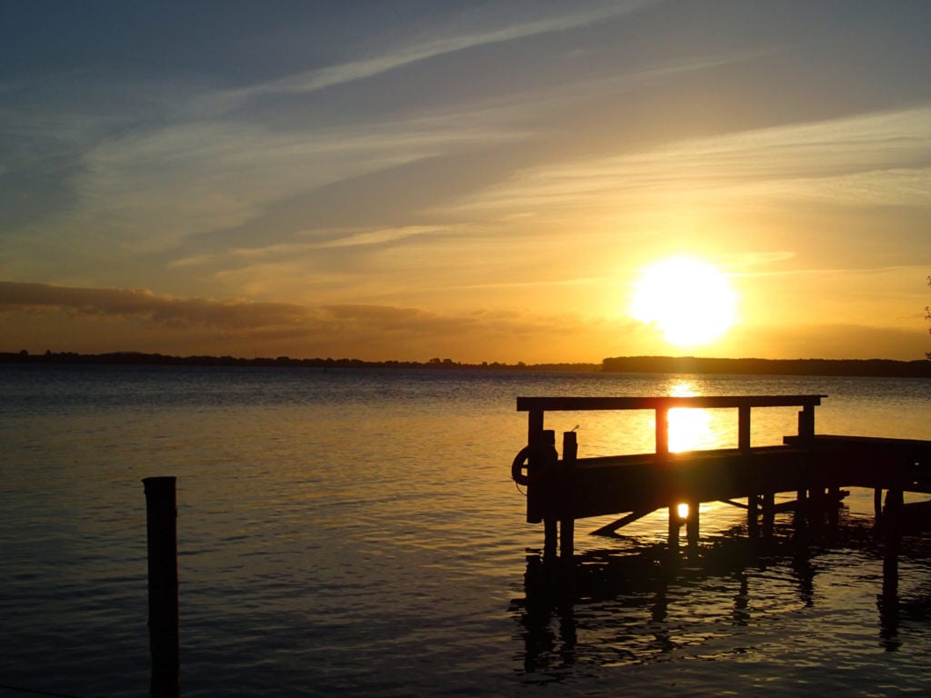 Sonnenuntergang am See, ein Steg im Vordergrund