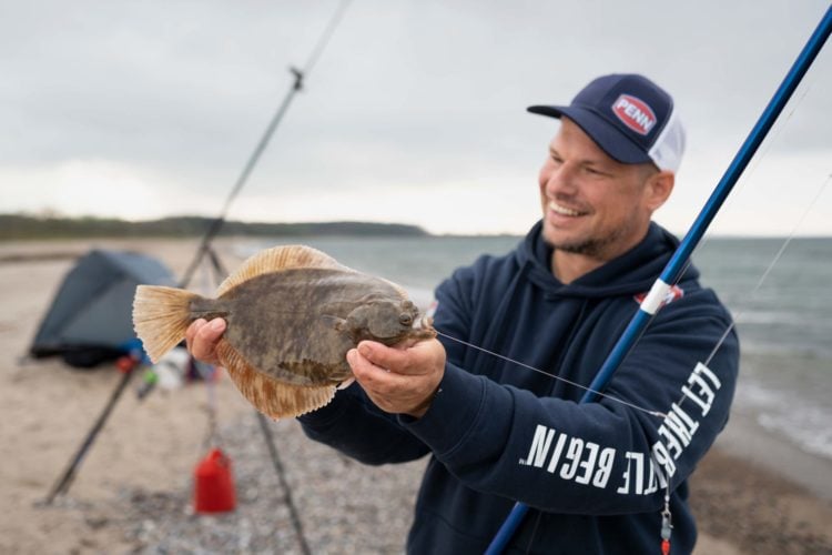 Angler mit Plattfisch, beim Brandungsangeln gefangen