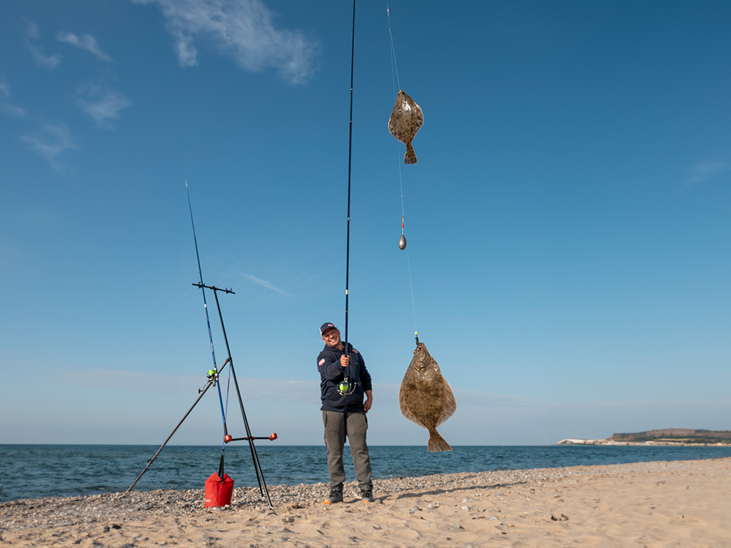 Angler präsentiert gefangene Plattfische am Haken