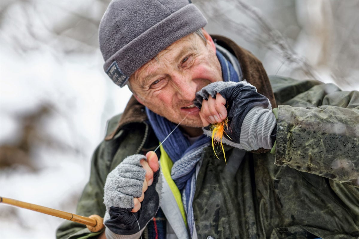 Ein Angler zieht den Knoten seiner Fliege mit dem Mund fest