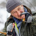 Ein Angler zieht den Knoten seiner Fliege mit dem Mund fest
