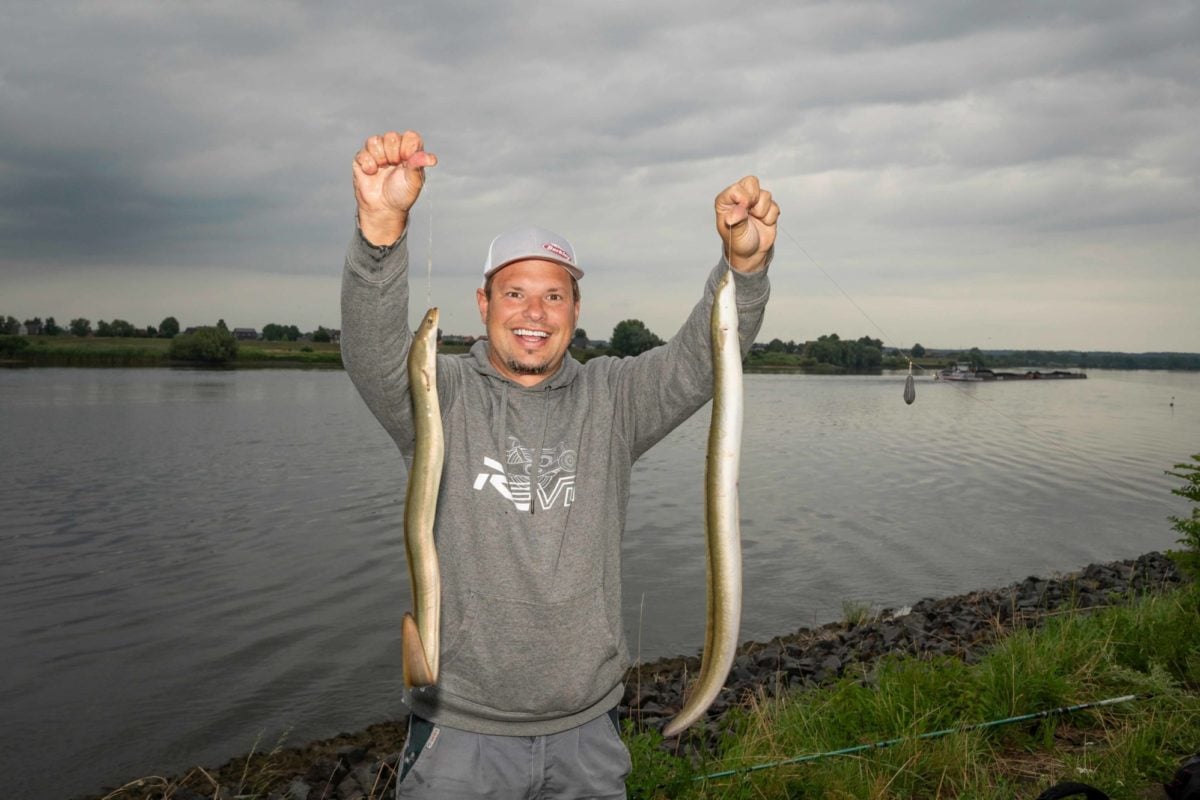 Fabian Frenzel mit zwei Aalen am Fluss