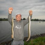 Fabian Frenzel mit zwei Aalen am Fluss