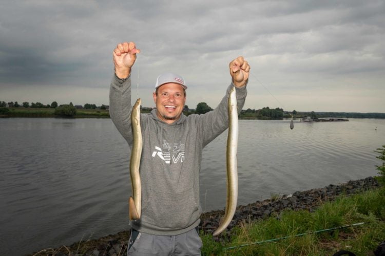 Fabian Frenzel mit zwei Aalen am Fluss