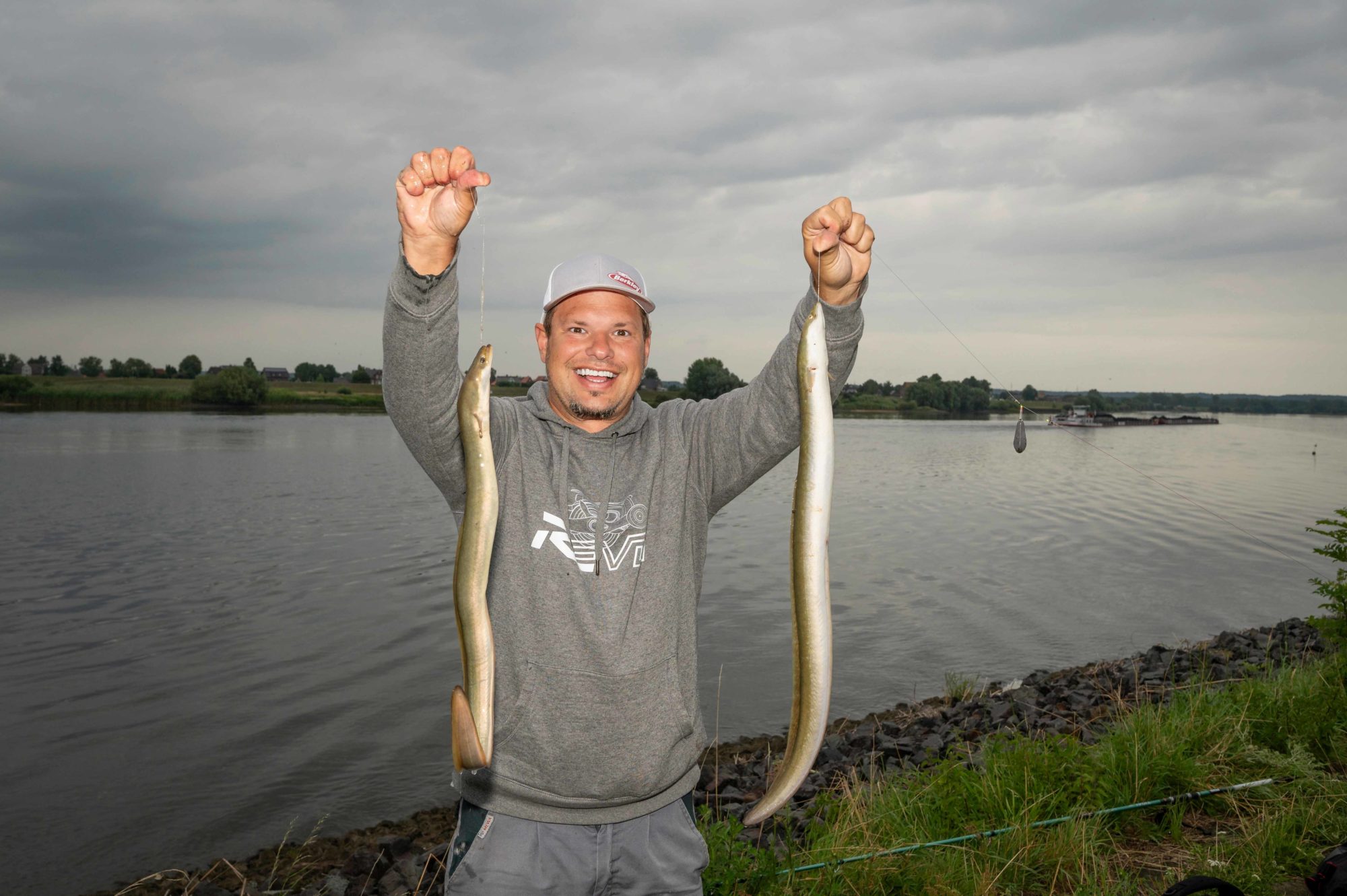 Fabian Frenzel mit zwei Aalen am Fluss