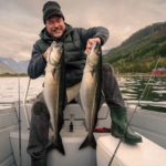 Angler mit zwei großen Seelachsen in einem norwegischen Fjord