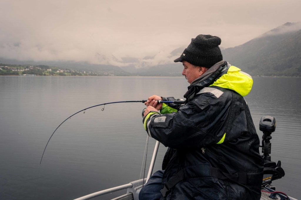 Angler drillt einen Fisch vom Boot in einem norwegischen Fjord