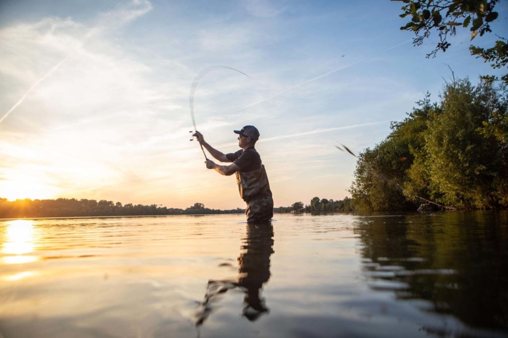Angler mit Wathose im Sonnenuntergang