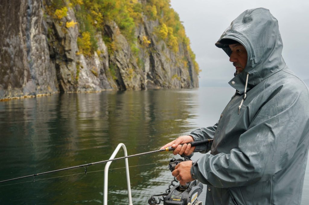Angler auf Boot vor Steilwand im norwegischen Fjord