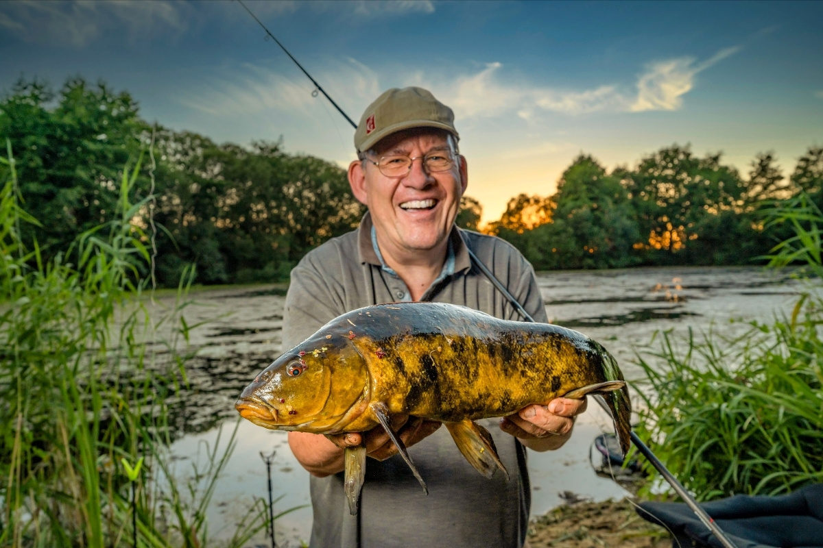 Angler mit Schleie auf einem Kraut-See