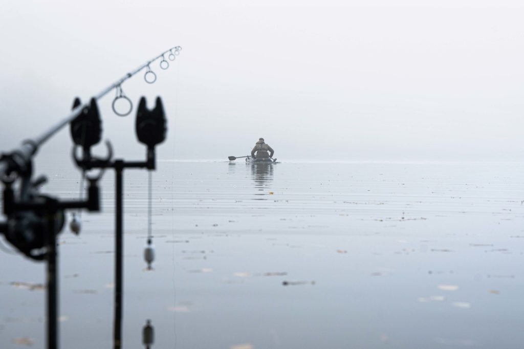Karpfenangler im Nebel, er hat seine Montage gerade vom Schlauchboot abgelegt