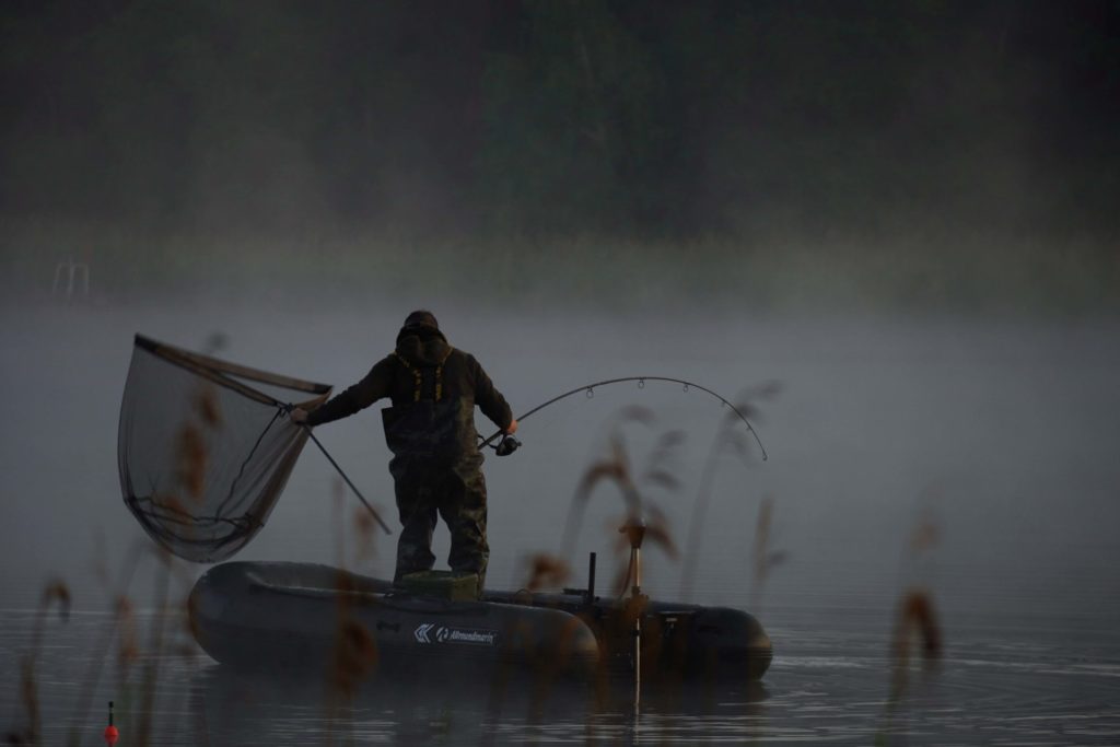 Angler drillt vom Schlauchboot im Herbst