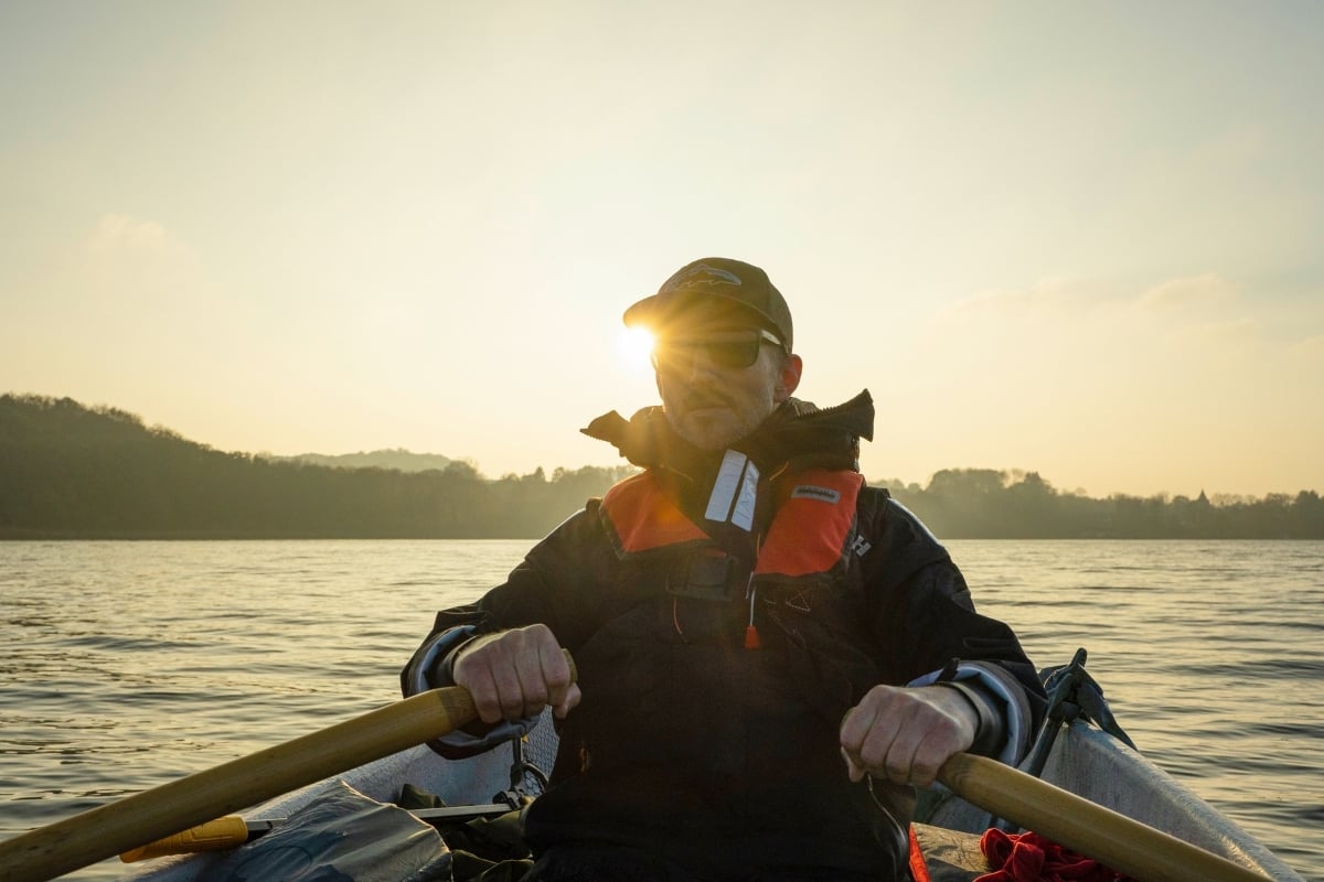 Bootsangler rudert in den Sonnenuntergang