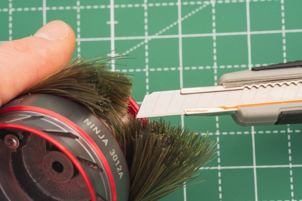 Monofilschnur wird mit einem Cuttermesser von der Spule geschnitten