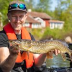 Angler mit Hecht im bellyboot, der hecht hat einen Reins Get Ringer am Offsethaken gefressen