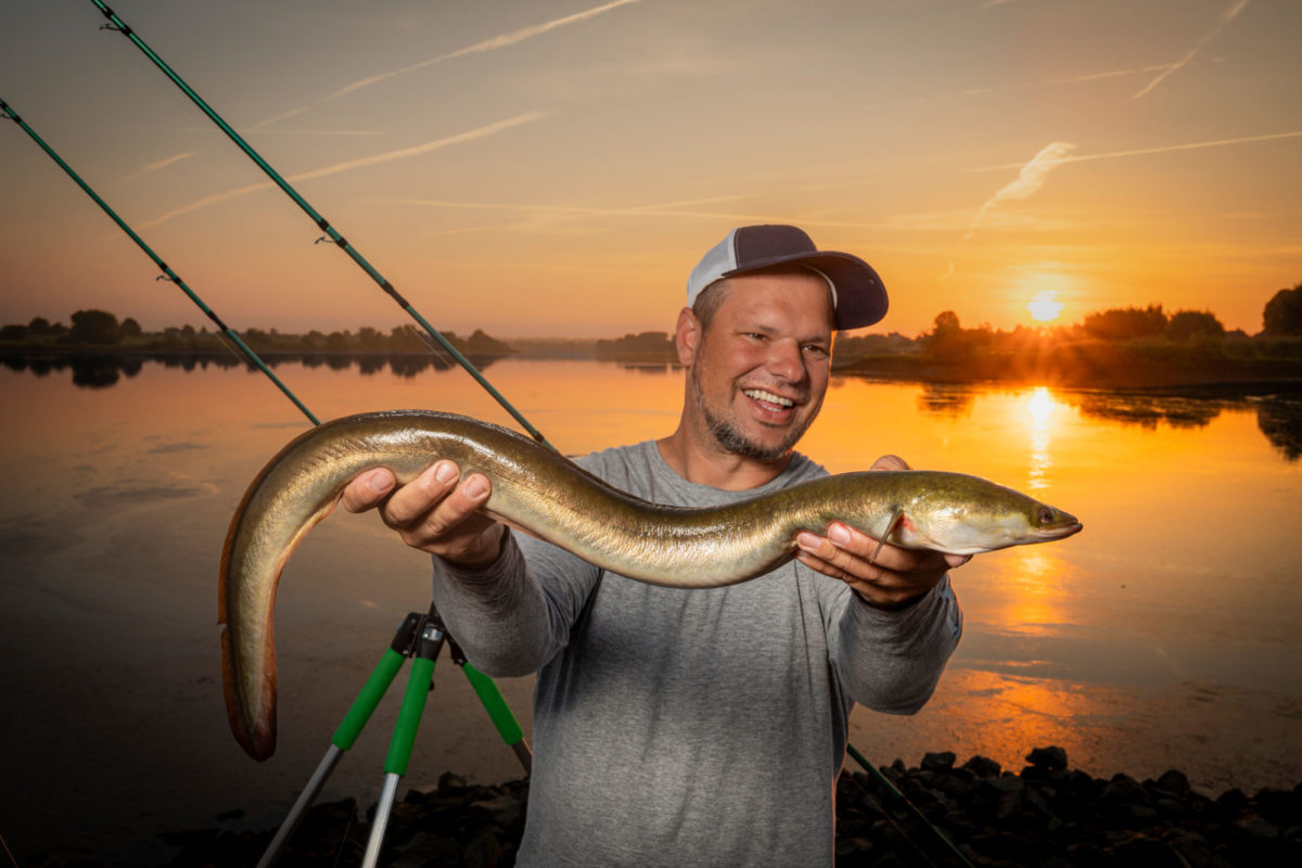 Aal Angler am Fluss in der Abenddämmerung