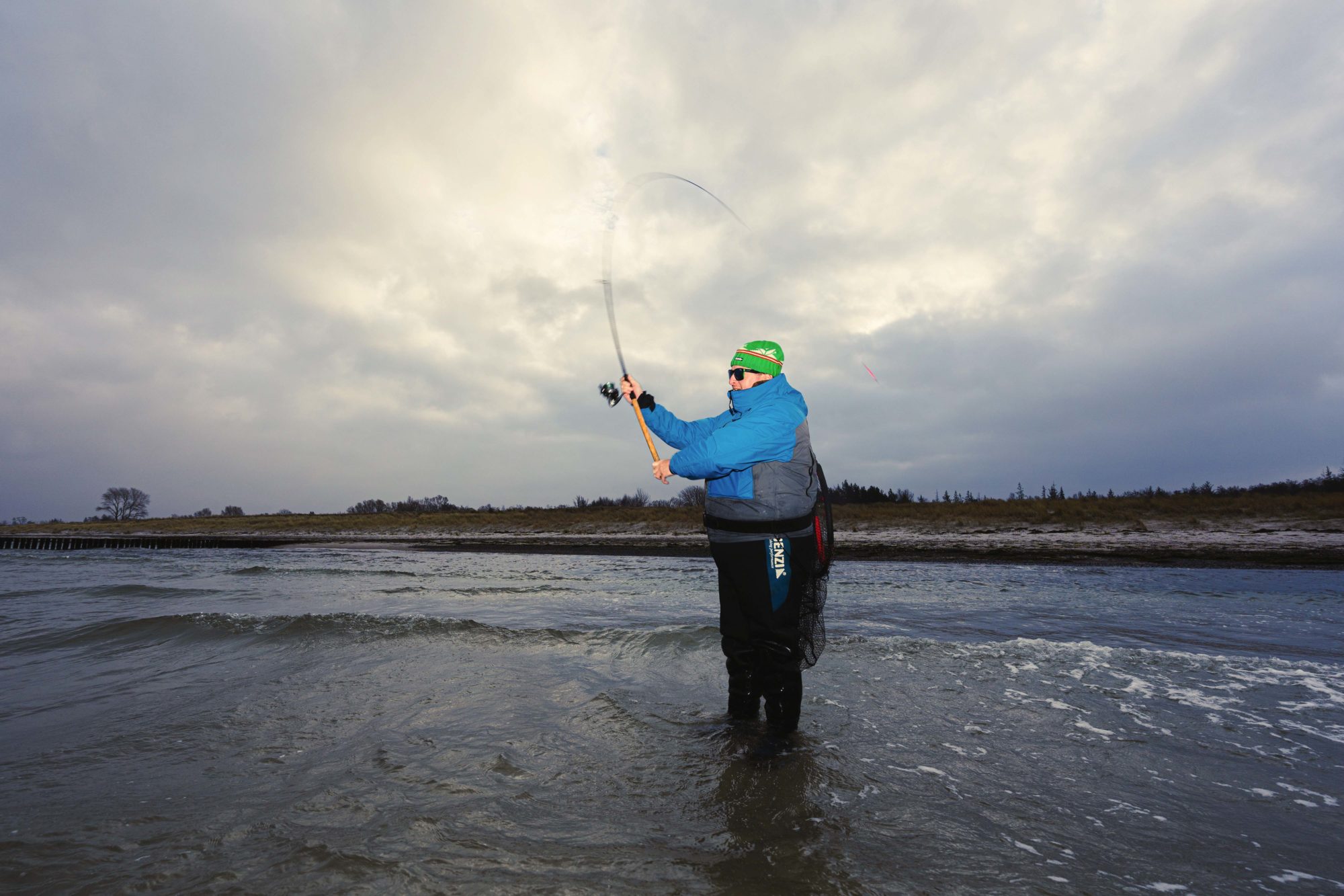 Angler wirft am Strand seine Meerforellenrute aus
