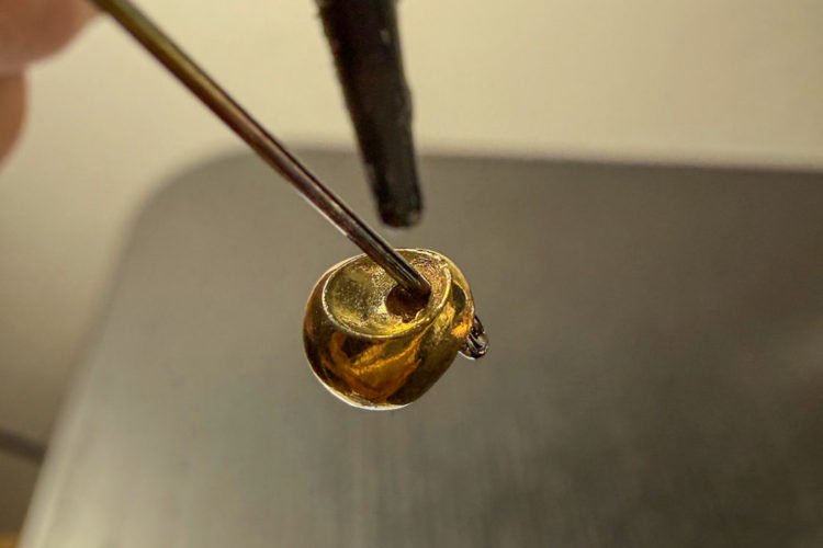 Ein Tropfen UV-Kleber kommt auf die Verbindung von Haken zu Perle. Micro Jig kleben